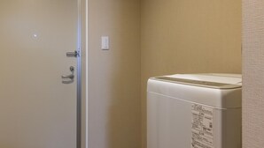 Una camera d'albergo con la porta chiusa, una lavatrice bianca e un condizionatore d'aria a parete.