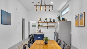 A modern kitchen with a central island, built-in shelves, and a dining area with a wooden table and chairs.