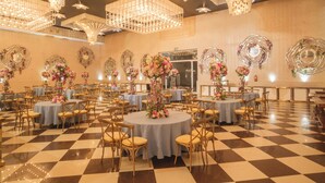 Une salle de banquet avec des tables rondes, des chaises, des compositions florales et des miroirs décoratifs fixés aux murs.