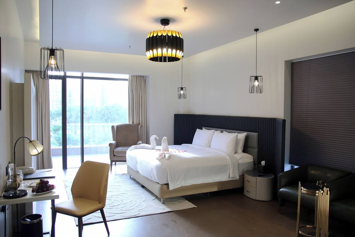 Ein modernes Hotelzimmer mit einem großen Bett, einem Schreibtisch, einem Sessel und einem Sofa.