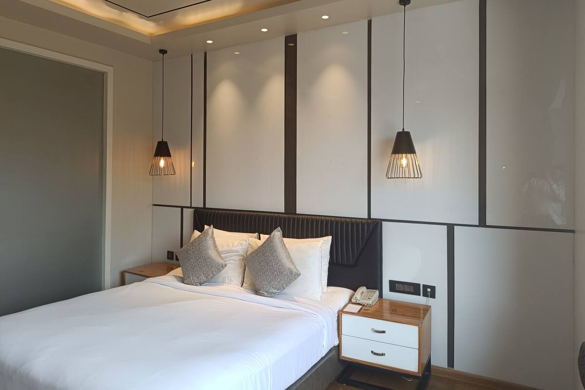 Ein modernes Schlafzimmer mit einem großen Bett, zwei Nachttischen, einem Beistelltisch und Pendelleuchten.