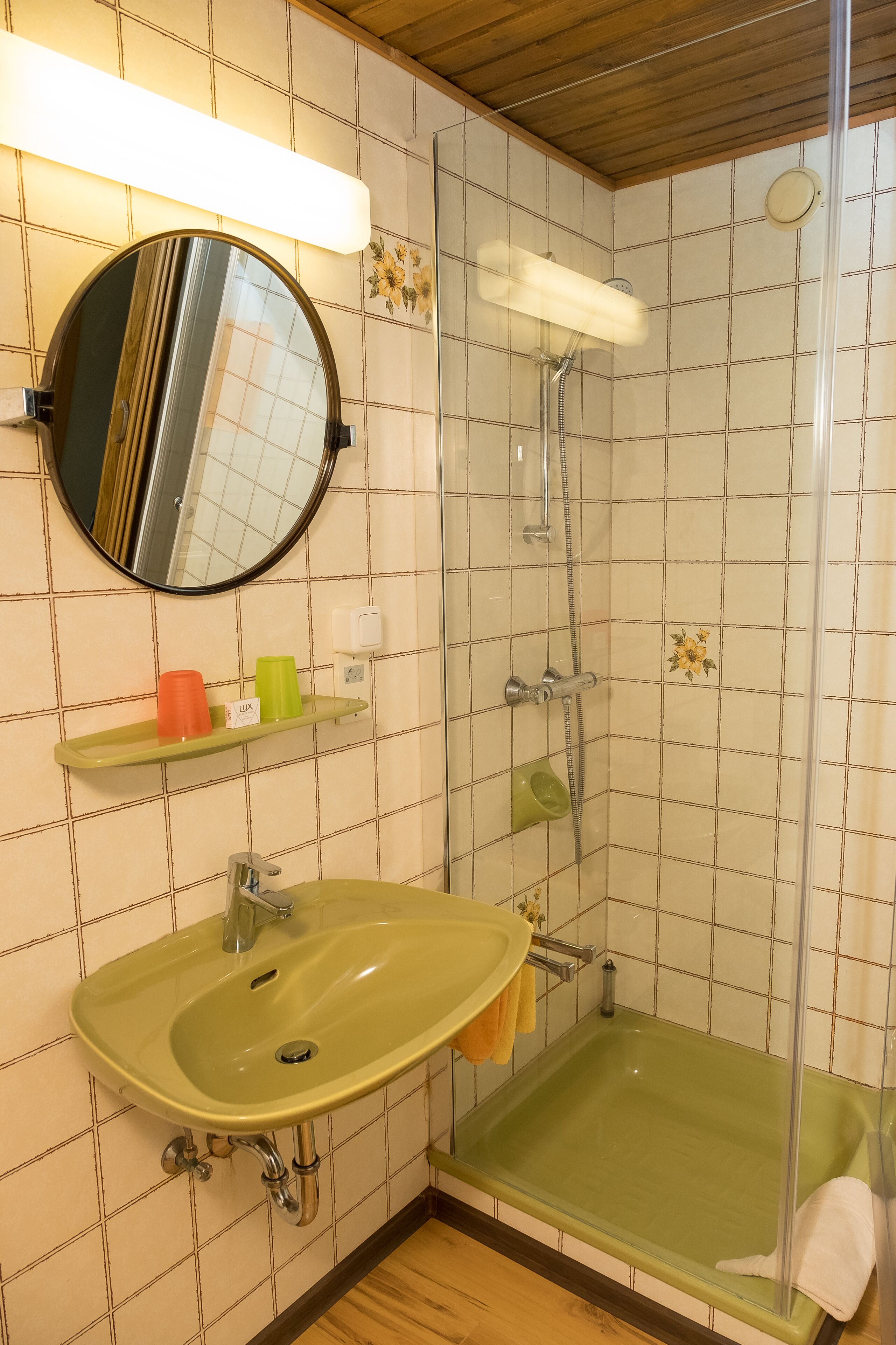 A bathroom with a green sink, a mirror, a shower, and a toilet.