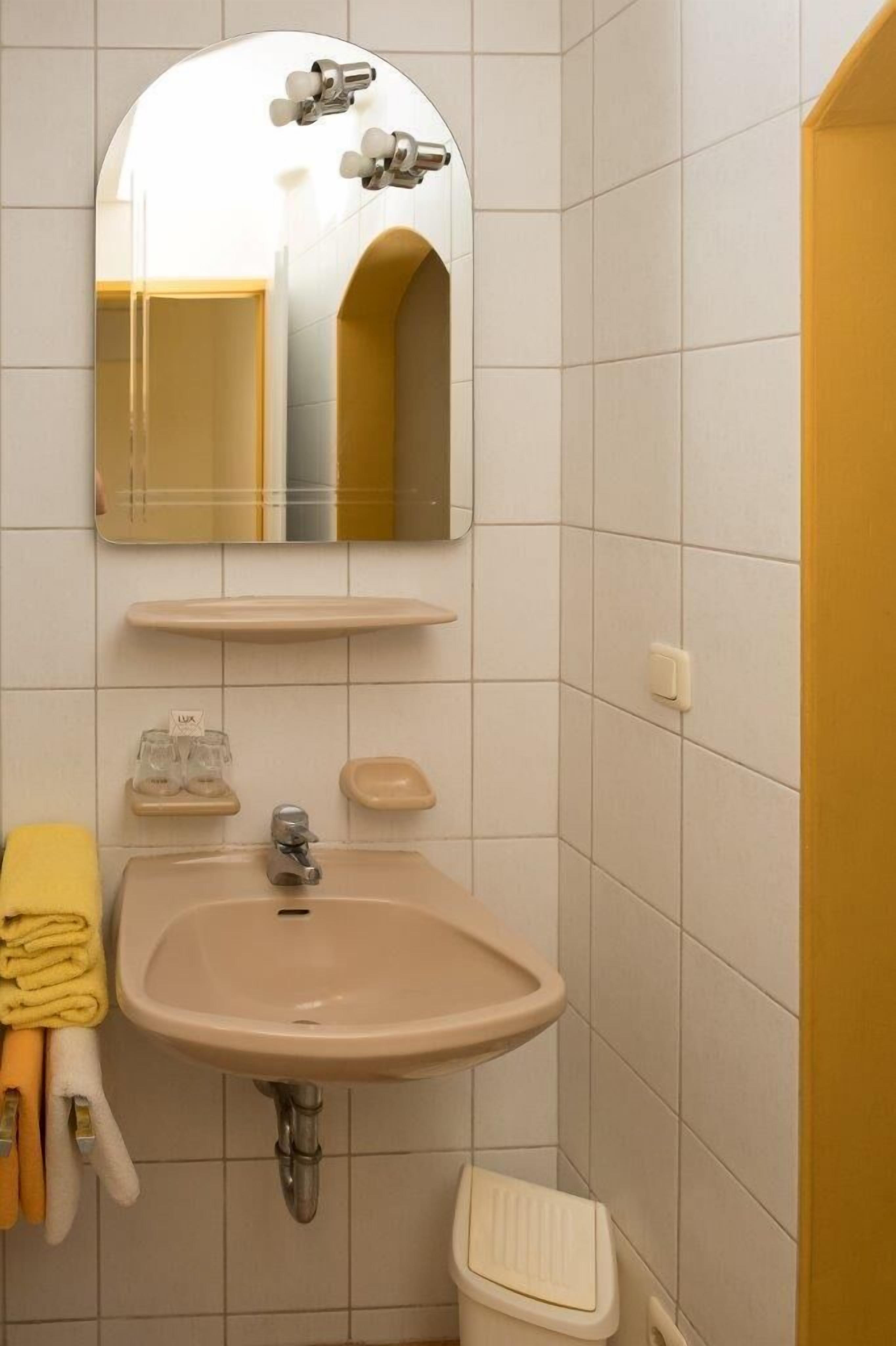 A bathroom with a sink, mirror, and towel rack.