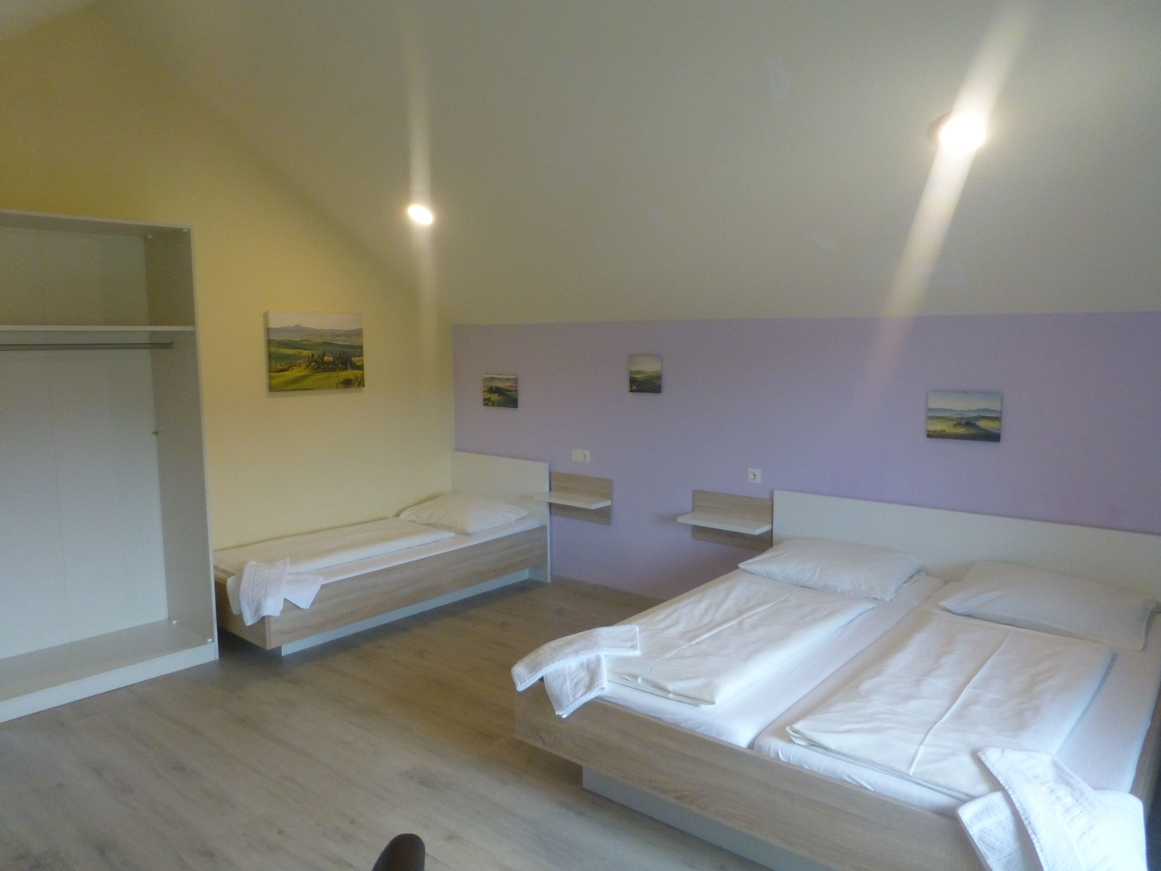 Ein Zimmer mit zwei Einzelbetten, einem Schrank und einem kleinen Tisch.