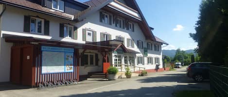 A two-story building with a traditional architectural style, featuring a prominent entrance with a covered porch and a signboard.