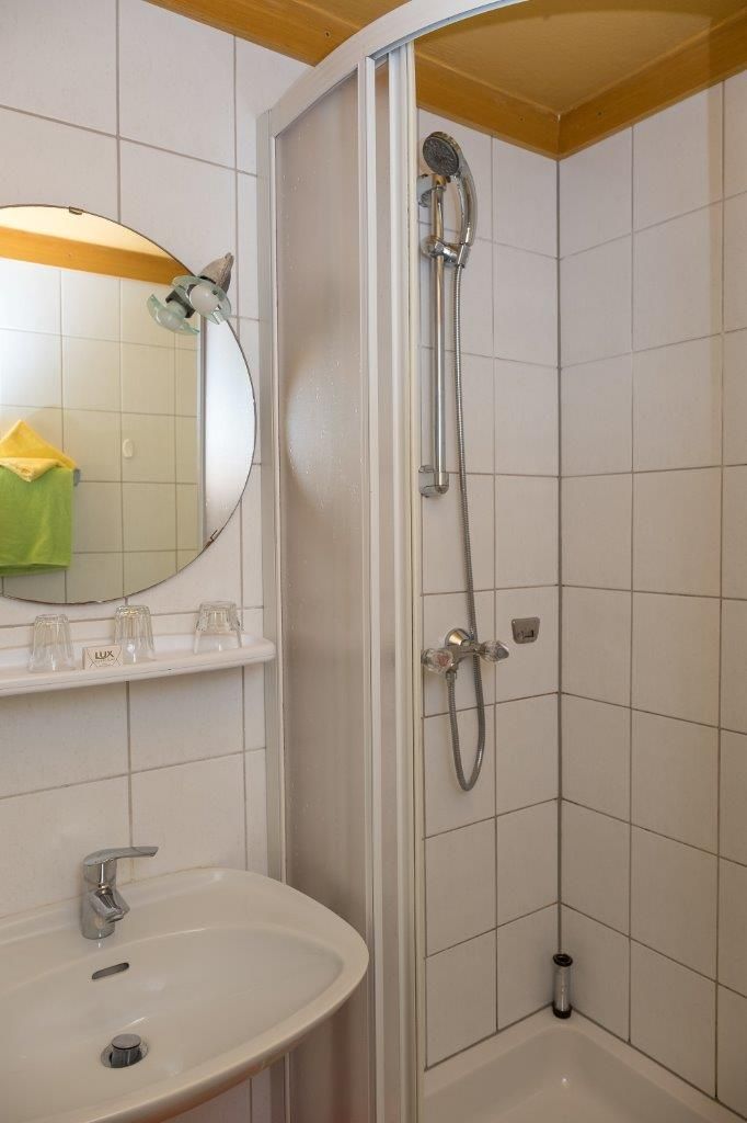 Une salle de bain avec un lavabo blanc, un miroir et une douche.