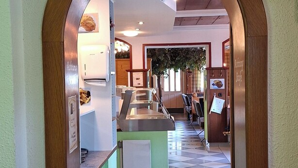 An arched entrance to a restaurant with a tiled floor and a sign above it. - Smartmotel (Straß im Attergau)