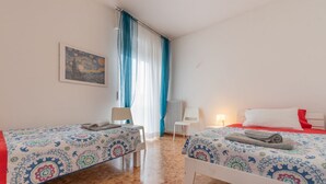 A hotel room with two beds, a chair, a table, a painting on the wall, and a window with curtains. - WATER -  WHOLE APARTMENT 4 GUESTS (Biandrate)