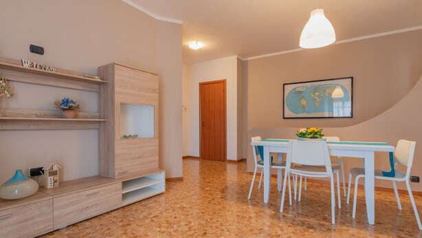 A modern dining area with a wooden cabinet, a white table with chairs, and a world map on the wall. - WATER -  WHOLE APARTMENT 4 GUESTS (Biandrate)