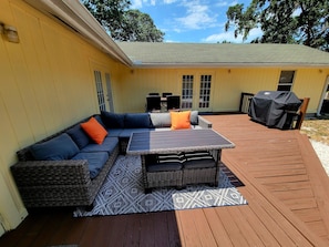 Eine Terrasse im Freien mit einer Eckcouch, einem Tisch und einem Grill.
