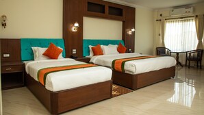 Ein Hotelzimmer mit zwei Betten, einem Schreibtisch und einem Sessel.