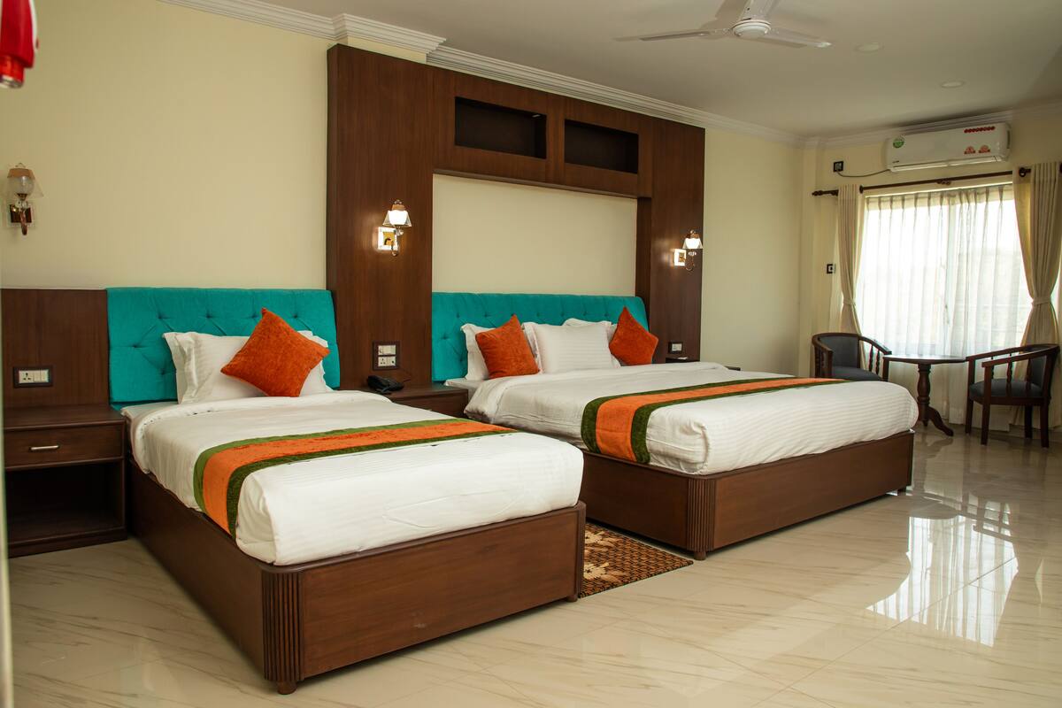 A hotel room with two beds, a desk, and a chair.