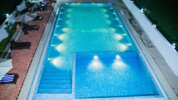 Ein rechteckiger Pool mit gefliestem Sonnendeck, umgeben von Liegestühlen und Sonnenschirmen.