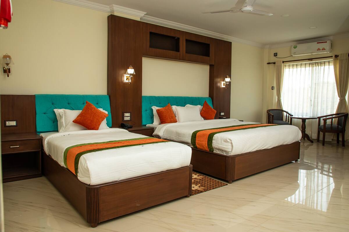 A hotel room with two beds, a desk, and a chair.