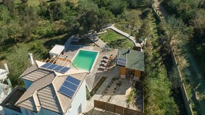 A residential property with a swimming pool, solar panels, and a stone pathway. - Villa Serenity (Corfu)