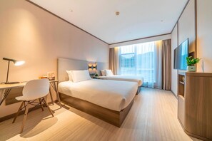 A hotel room with a large bed, a desk with a chair, a TV, and a plant. - Hanting Hotel (Chongqing)