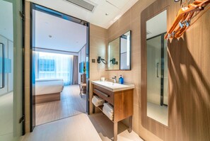 A modern hotel bathroom with a large mirror, a wooden vanity, and a shower area. - Hanting Hotel (Chongqing)