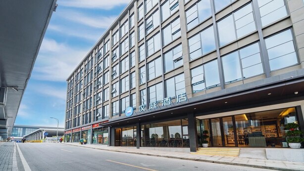 A modern hotel with a large glass facade, multiple floors, and a prominent entrance with a covered area.