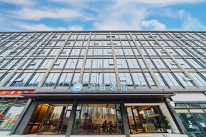 Un hotel moderno con una fachada de ventanas en forma de cuadrícula y un letrero que indica que es el Hotel Hanjiang.