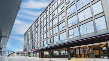 A modern hotel with a large glass facade, multiple floors, and a prominent entrance with a covered area.