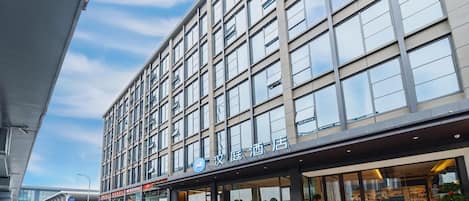 A modern hotel with a large glass facade, multiple floors, and a prominent entrance with a covered area.