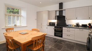 Una cocina moderna con armarios blancos, una mesa de comedor de madera y una campana extractora negra.
