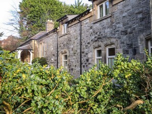 A stone building with multiple windows and a small porch area. - 1 The Stables (Grange-over-Sands)