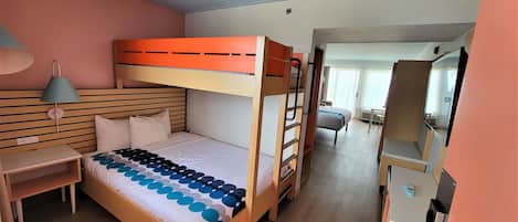 Habitación con literas, un escritorio, una silla, una lámpara y una ventana con cortinas.