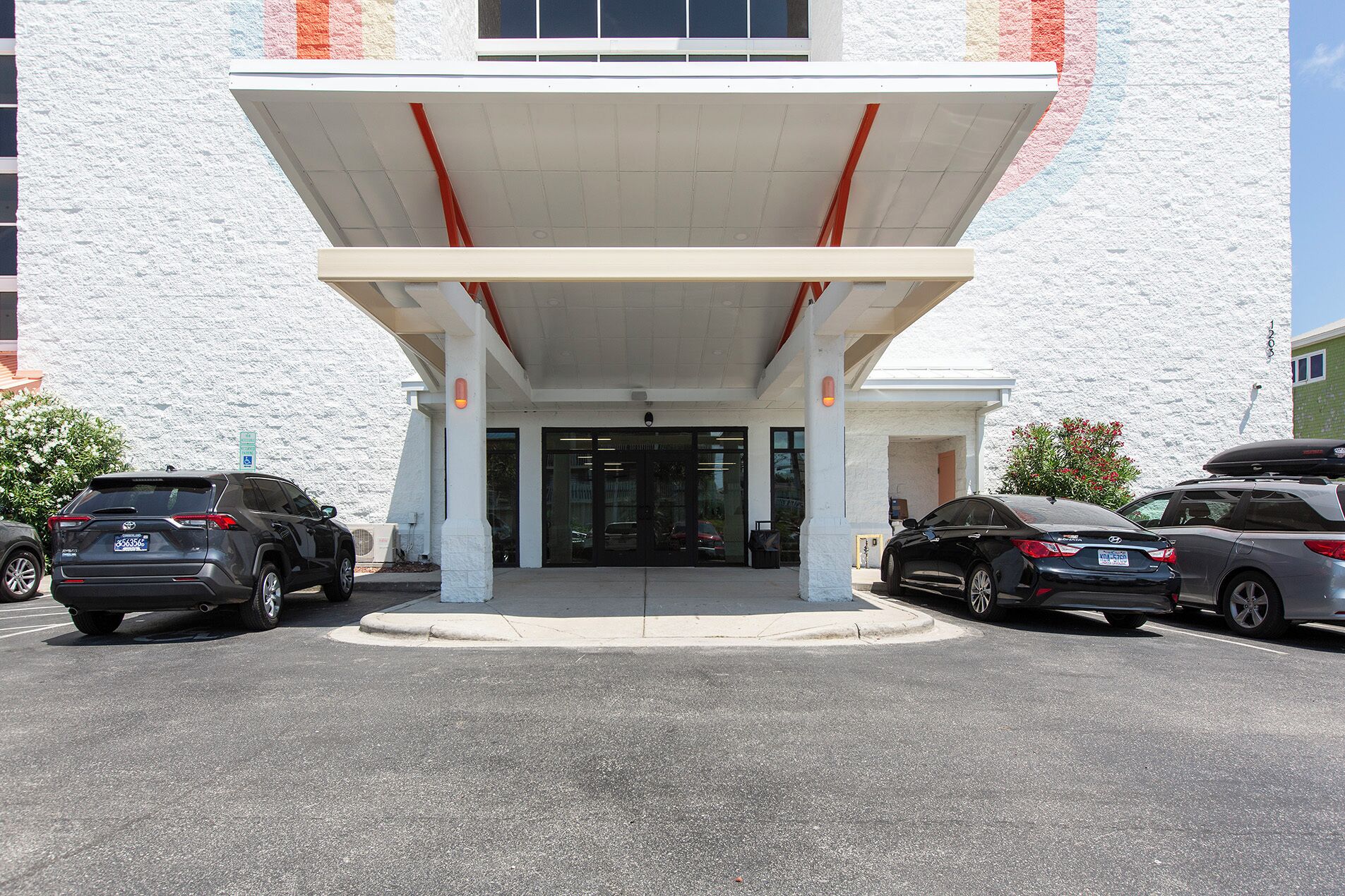 A building with a covered entrance, parking lot, and a sign indicating handicap accessibility.