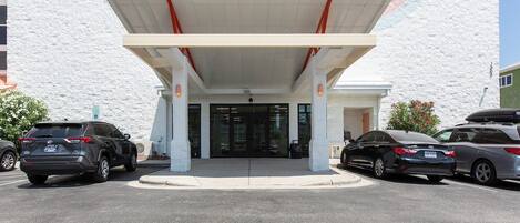 A building with a covered entrance, parking lot, and a sign indicating handicap accessibility.