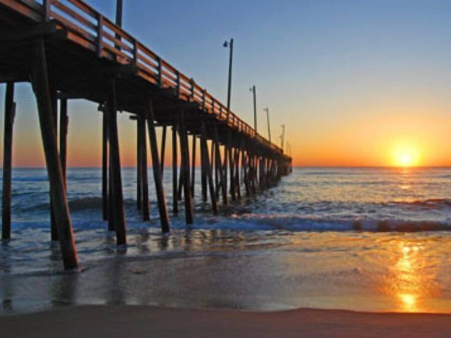 A pier extending into the water with a sunset in the background.