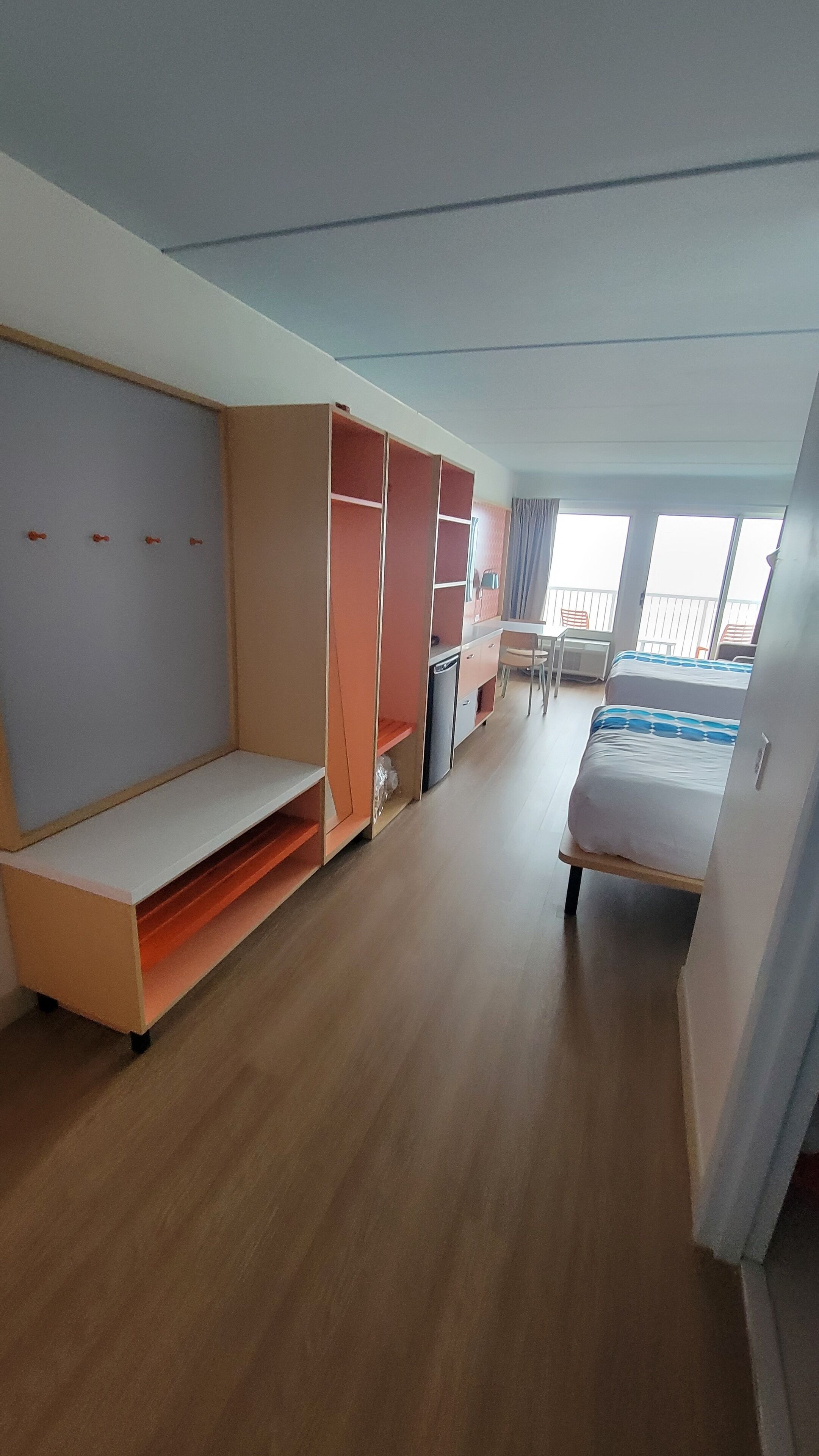 Une chambre comprenant un lit, un bureau, une armoire et une petite kitchenette.