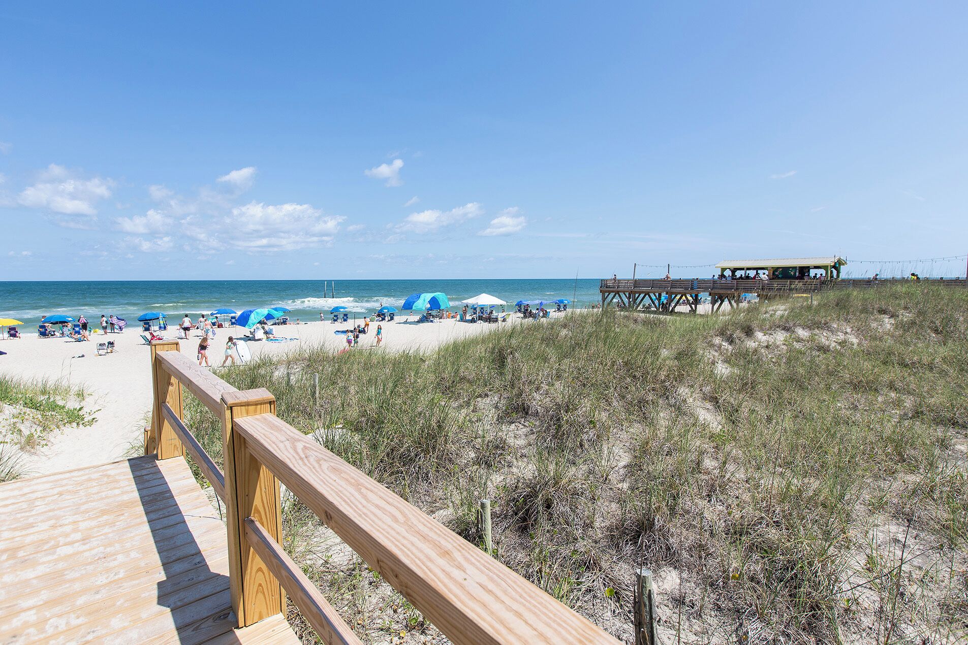 A beach with a wooden boardwalk leading to a beachside structure.