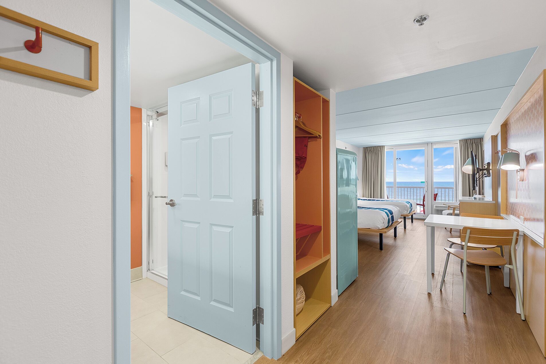 Een hotelkamer met een groot bed, een bureau en uitzicht op zee.