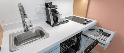 Eine kleine Küche mit Spüle, Kaffeemaschine, Mikrowelle und Geschirrspüler.