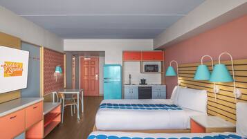 A hotel room with a bed, a desk, a chair, a kitchenette, and a bathroom.