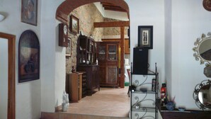 A hallway with a stone wall, wooden cabinets, and a tiled floor. - Casa do Castelao (Loulé)