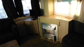 Cocina compacta con microondas integrado, un refrigerador pequeño y una ventana con cortinas.