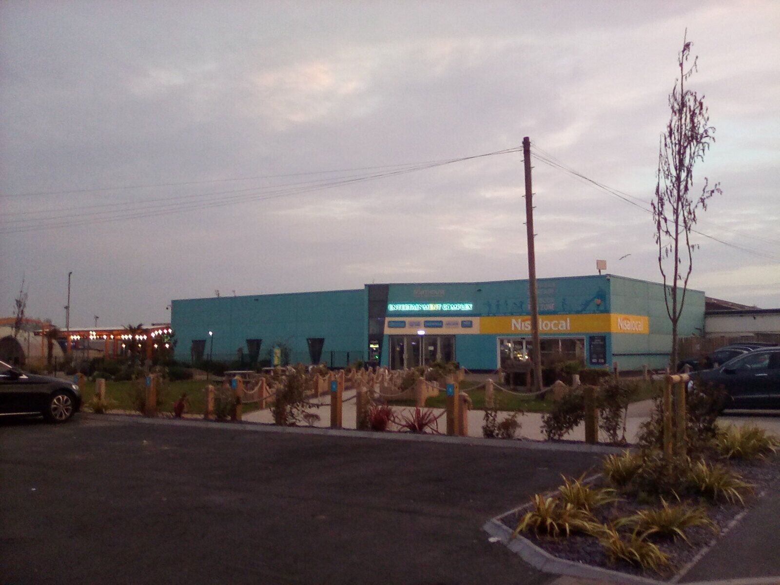 A building with a blue and yellow sign, a parking lot, and some landscaping.