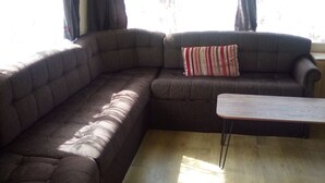 Sala de estar com um sofá seccional marrom escuro, um travesseiro listrado e uma pequena mesa de centro de madeira.