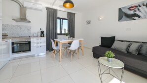 A modern kitchen with white cabinetry, a built-in oven, and a dining area with a table and chairs. - Villa Vistamar with private heated pool for 16 (Novalja)