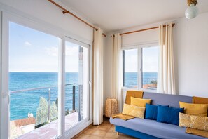 A balcony with a view of the sea, a sofa with cushions, and a wicker basket. - Majordoms - Cau del Llop, Llaça (Llança)