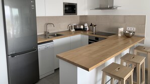 A modern kitchen with a stainless steel refrigerator, built-in oven, and microwave. - frontline 2 bedroom apartment (Tías)