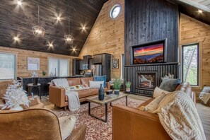 A cozy living room with a fireplace, leather sofas, and a wooden ceiling.
