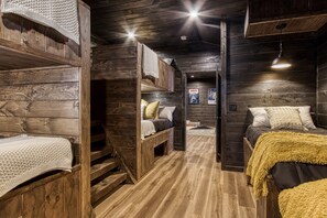 A cabin-style room with wooden walls and floors, bunk beds, and a cozy atmosphere.