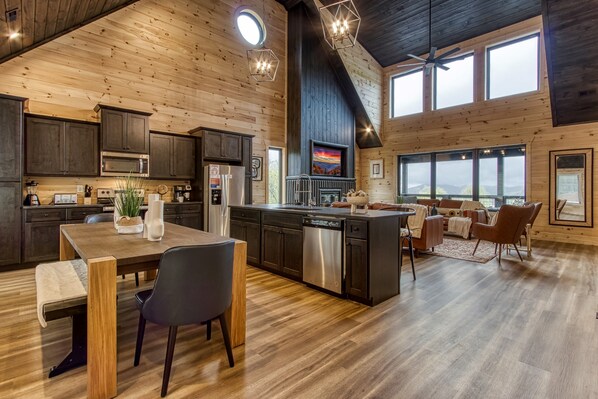 A spacious kitchen with dark cabinets, a central island, and a dining area with a bench and chairs.
