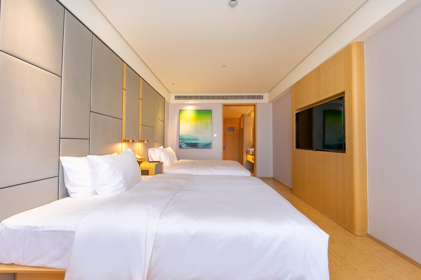 Habitación de hotel con dos camas, televisión, un cuadro y un armario de madera.