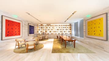A modern conference room with a long table, chairs, a patterned wall, and framed artwork.