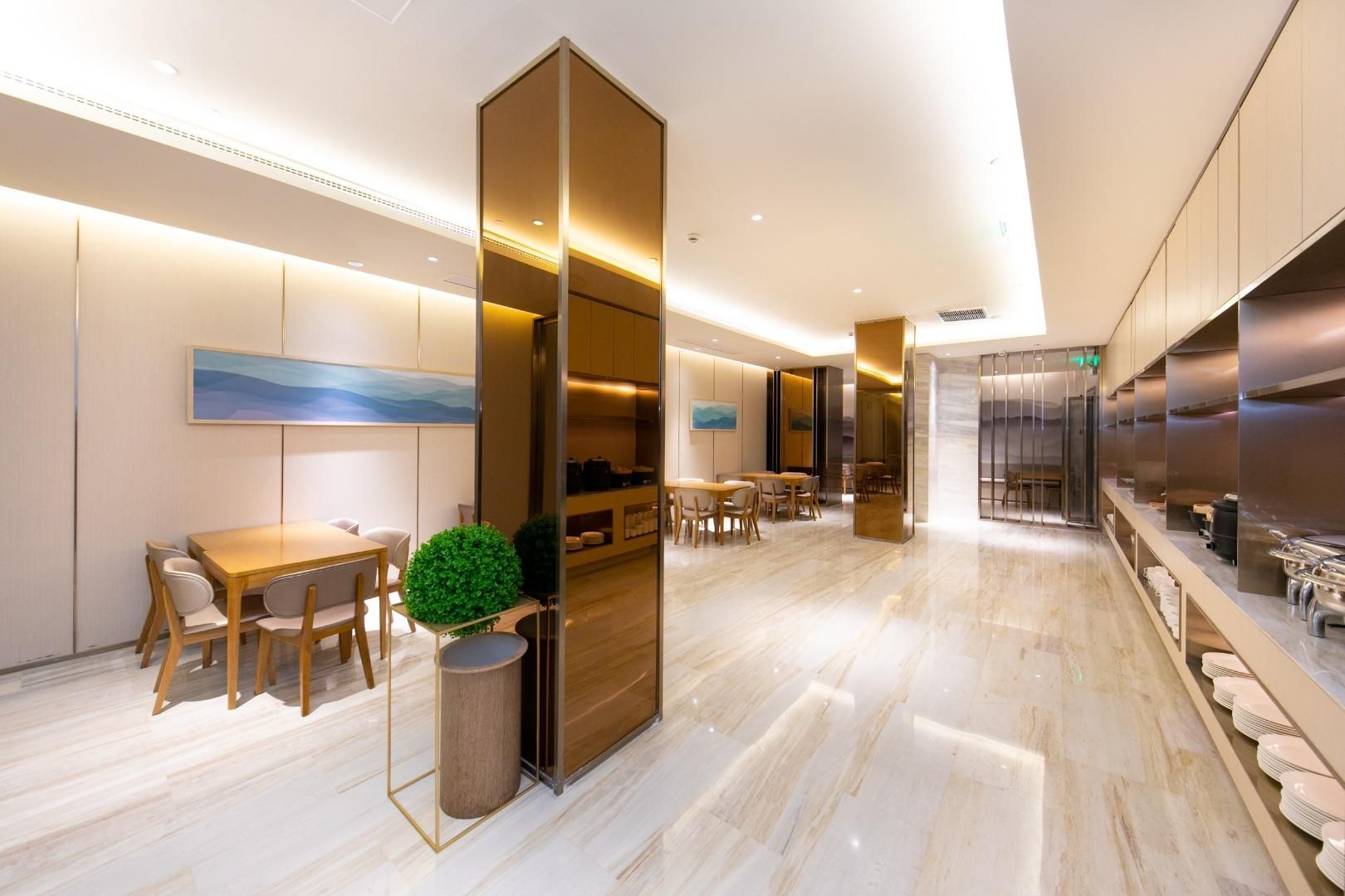 A modern hotel lobby with a marble floor, wooden furniture, and a large plant.