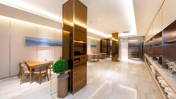 A modern hotel lobby with a marble floor, wooden furniture, and a large plant.
